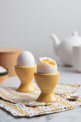 Soft-boiled eggs in yellow egg cups for cozy breakfast in the kitchen, natural and healthy eating,...