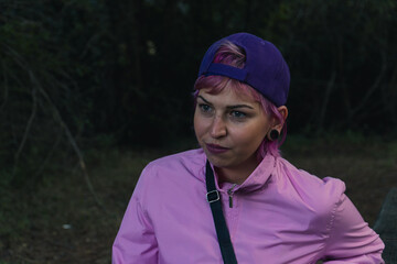 Beneficios de estar en contacto con la naturaleza, chica senderista observando el entorno de la naturaleza, chica con gorra morada y chaqueta rosa en medio de la naturaleza
