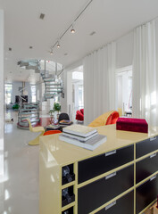 Modern interior of luxury apartment. White walls. Yelow, orange chairs. Books on table.