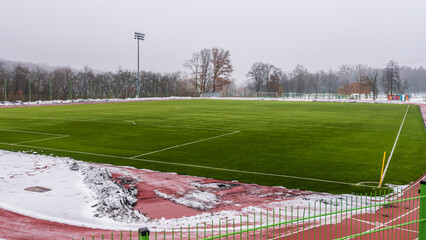 Soccer training field with artificial grass. Fallen snow on the treadmill