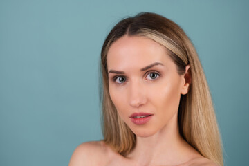Naklejka premium Close beauty portrait of a topless woman with perfect skin and natural make-up, plump nude lips, on a blue background.