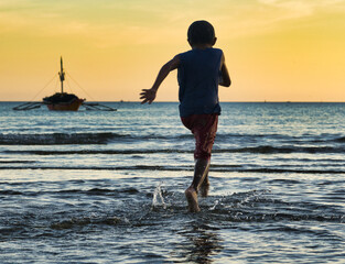 Waterboarding fun at sunset. for village children Bulalacao fishing village, Oriental Mindoro, Philippines