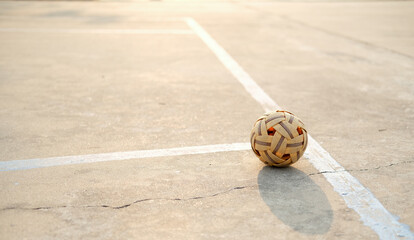 A rattan ball is placed on the concrete floor of the court during the evening hours. have a copy...