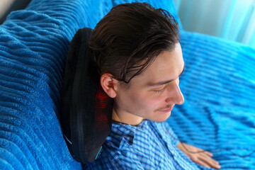 Electric massage cushion with infrared warming areas. Milineal man relaxes at home