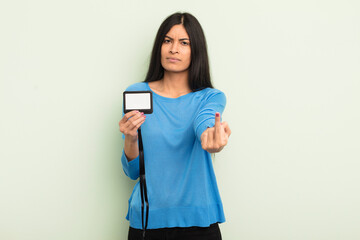 young pretty hispanic woman feeling angry, annoyed, rebellious and aggressive. accreditation pass...