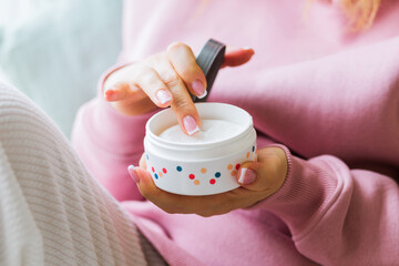 female fingers touching the cream in the container