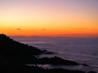 The rocks and the sea with the sunset in the background.