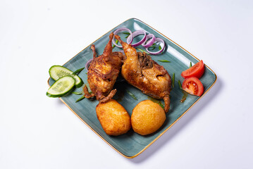 two fried quails with potatoes and fresh cucumbers, tomatoes and onions. on a white background