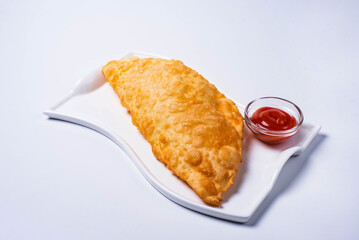 cheburek with ketchup. a culinary product in the form of a semicircle of unleavened dough with a filling of chopped fatty lamb, onions, spices. on a white background