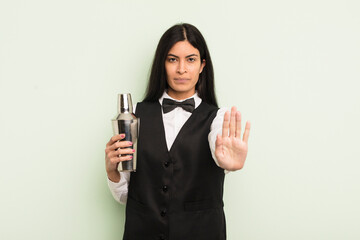 young pretty hispanic woman looking serious showing open palm making stop gesture. cocktail bartender concept