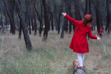 NIña pequeña pelirroja con vestido rojo en el bosque