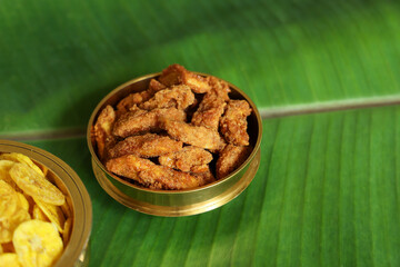 sweet banana chips in golden plate for Onam festival in Kerala India. Indian snacks in banana leaf.