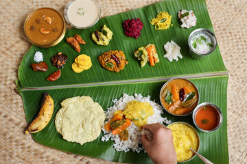 Woman eating with hand traditional Onam sadhya rice Sambar Rasam parippu dal curry ghee Pappadom Payasam on banana leaf Onam Vishu Pongal Diwali festival vegetarian food Kerala Tamil Nadu South India.