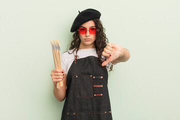 young pretty hispanic woman feeling cross,showing thumbs down. artist concept