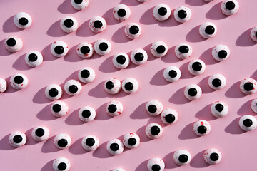 Lots of round plastic doll eyes on a pink background. Flat lay.