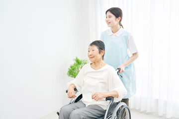 介護士と車椅子に乗る高齢者　室内