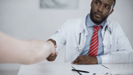 african american doctor shaking hands with patient.