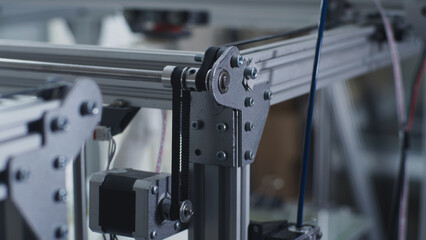 Soft focus of mechanism of contemporary 3D printer printing plastic model in modern design workshop