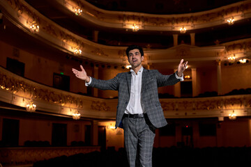 young caucasian brunette man in elegant stylish gray suit performing opera or singing at a concert...