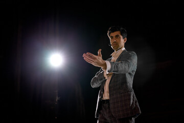 attractive and confident successful guy speaking at corporate business coaching and training auditorium conference room talking giving motivation training from speaker stage. success concept