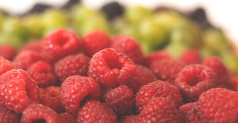 Summer fruity berry background. Table with berries and fruits. Summer breakfast, vacation, morning, sun. Berries, raspberries, blackberries, gooseberries. Vase with berries and fruits. 