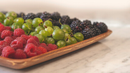 Summer fruity berry background. Table with berries and fruits. Summer breakfast, vacation, morning, sun. Berries, raspberries, blackberries, gooseberries. Vase with berries and fruits. 