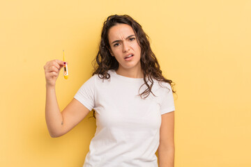 young pretty hispanic woman feeling puzzled and confused. thermometer concept