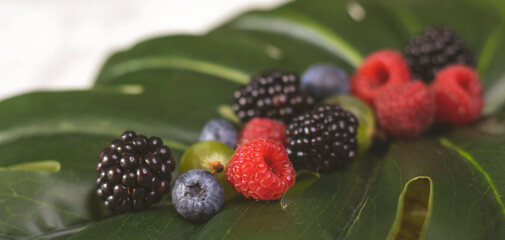 Summer fruity berry background. Table with berries and fruits. Summer breakfast, vacation, morning, sun. Berries, raspberries, blackberries, gooseberries. Vase with berries and fruits. 