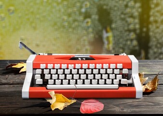 Old typewriter on a table with autumn leaves