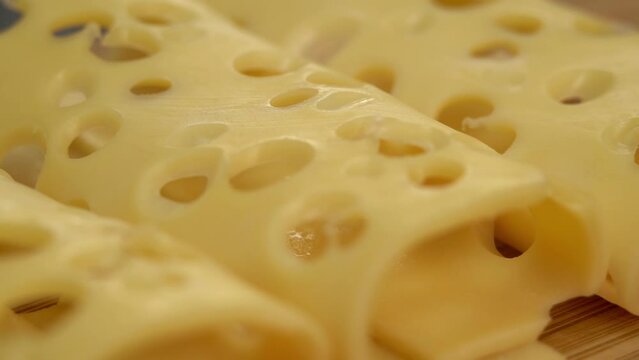 Camera movement on maasdam cheese with large holes. Macro food background. Farm dairy food