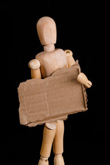 a wooden man holds a brown cardboard sign on a black background