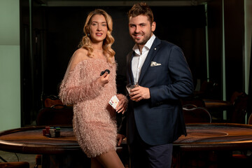 Couple of successful gamblers standing near poker table in casino