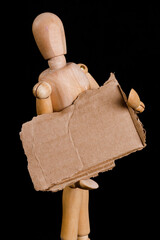 a wooden man holds a brown cardboard sign on a black background