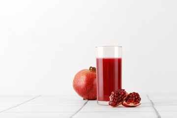 Glass of Fresh pomegranate juice with fresh pomegranate fruits on tile background for menu and mock up