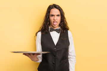 young pretty hispanic woman feeling disgusted and irritated and tongue out. waiter and tray concept