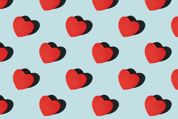 Paper red heart shape gift boxes pattern with shadows. Pattern of red heart shape gift boxes on a blue background with hard shadows. Valentine's card.