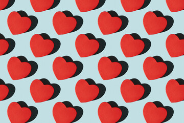 Paper red heart shape gift boxes pattern with shadows. Pattern of red heart shape gift boxes on a blue background with hard shadows. Valentine's card.