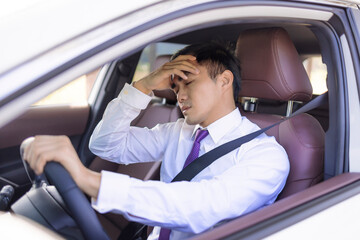 Sick, tired business man driving the car and  waiting in  traffic jam