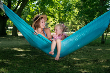 Fototapeta na wymiar loving family spends time together in summer time enjoy the little things. slow life. mom and little daughter relax in a hammock in the summer in the garden 