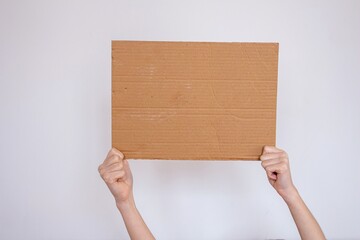 Hand holding blank cardboard box isolated on white background.