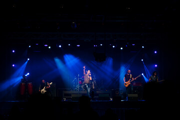 Rock group performing before the audience at a live concert.