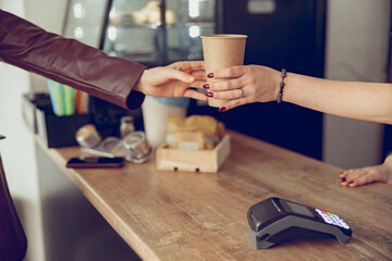 Female barista hand giving cup of coffee to woman