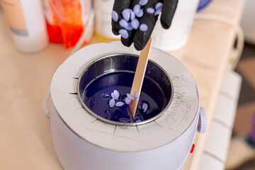 close-up. melted lilac wax for depilation and epilation and a hand in black rubber gloves