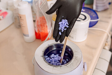 close-up. melted lilac wax for depilation and epilation and a hand in black rubber gloves