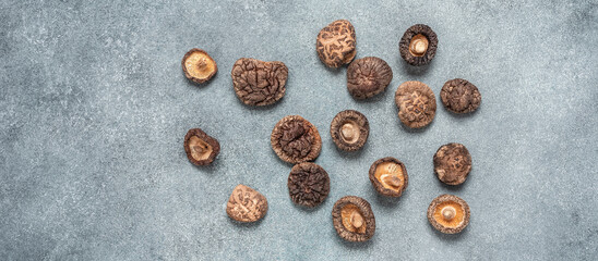 Dried shiitake mushrooms. Gray concrete grunge background. Top view, flat lay, banner.