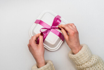 Woman holding Bento Cake. Portioned trandy dessert for one person in eco box with purple ribbon, small cake. Pink ribbon.