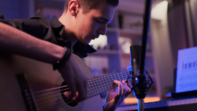 Man plays guitar. Young man plays a musical instrument. Musician records his composition in a music Studio using professional microphone