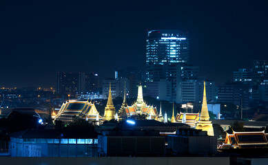 Fototapeta premium The Grand Palace illuminate gold light beatifully with surrounded buildings on night scene on blue tone color, The Grand Palace is where the royal ceremonies, Bangkok, Thailand