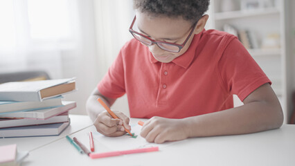 Fototapeta na wymiar Black boy drawing New Year postcard during lesson in elementary school, artwork