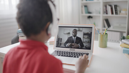 Pupil learning foreign language with online tutor, sitting in front of laptop